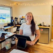 Abby smiling behind the counter at Lines & Vines Coffee
