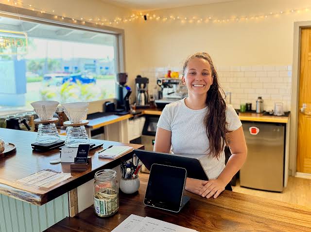 Abby smiling behind the counter at Lines & Vines Coffee