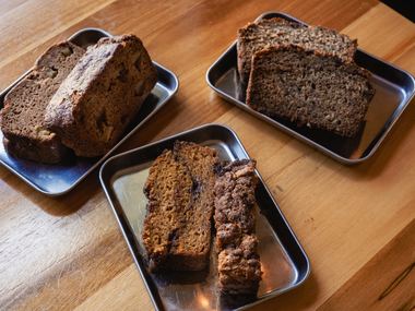 All three loaf breads sliced on steel trays: apple on the left, pumpkin in the center, banana chocolate chip on the right