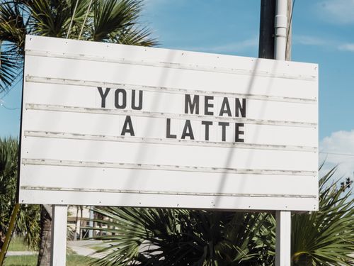 The shop's roadside marquee sign reading YOU MEAN A LATTE, against palm trees and a blue sky